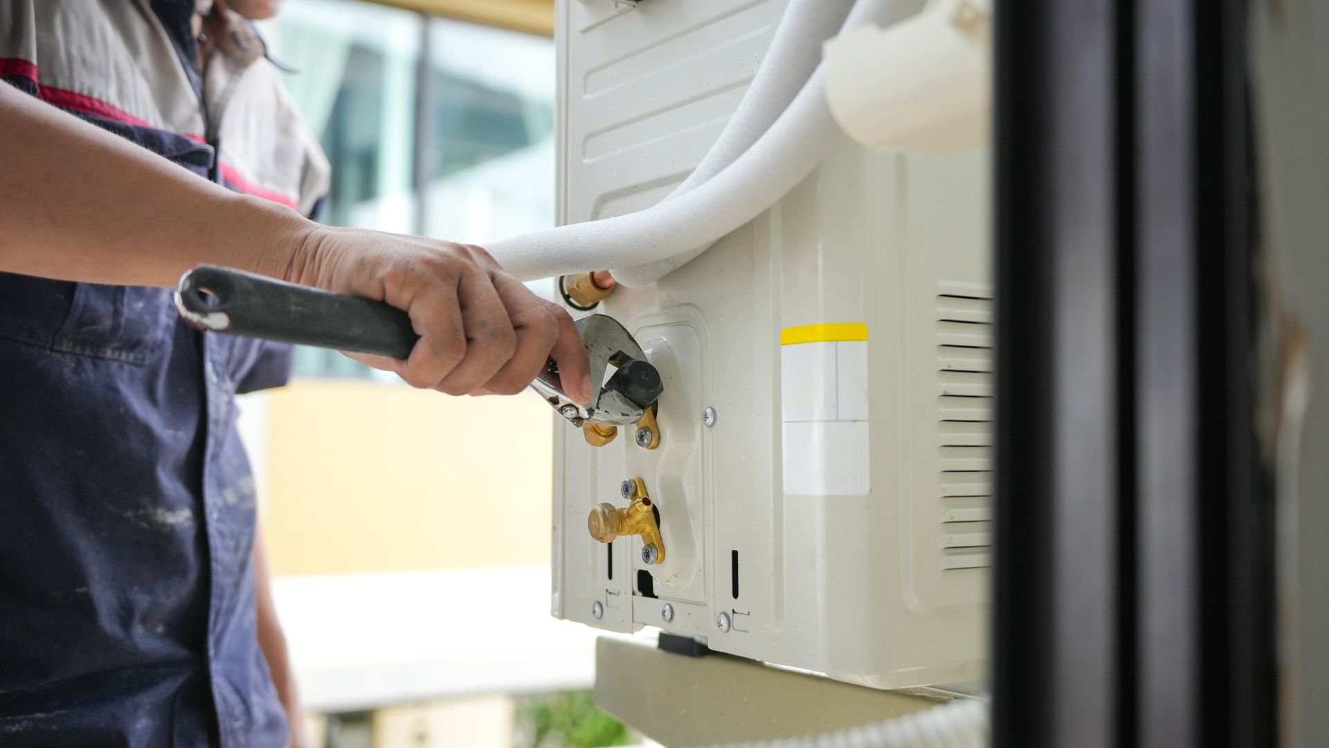 Technician installing or repairing an air conditioning unit with wrench