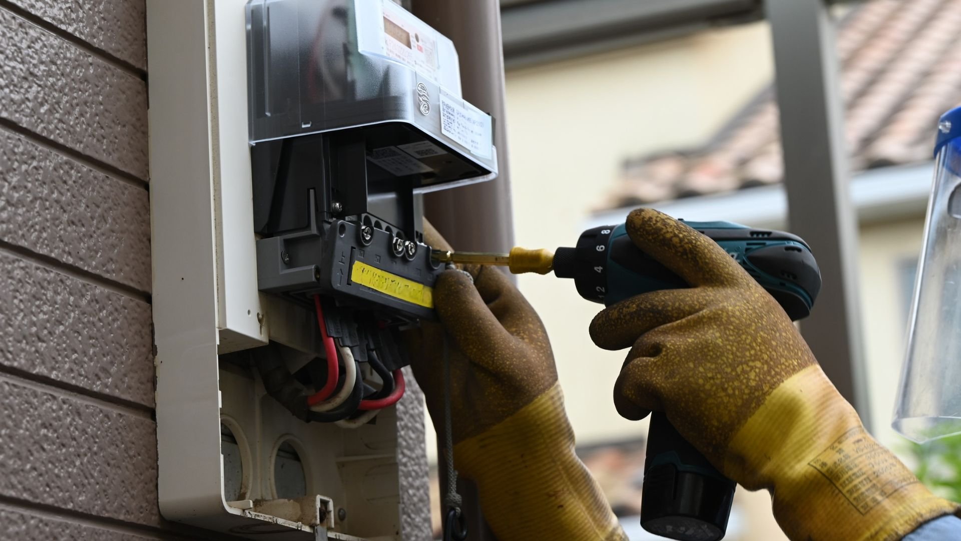 Technician using drill to repair electrical equipment with protective gloves
