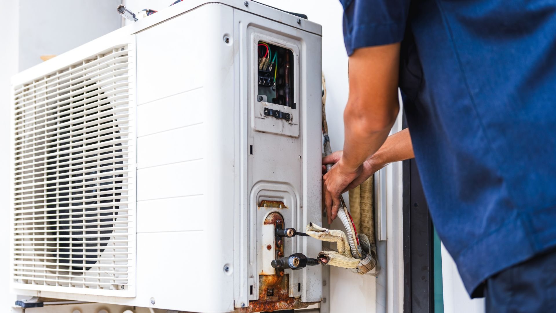 Technician repairing an air conditioning unit, exposing internal components