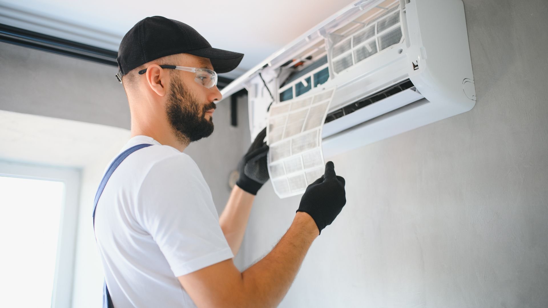 Technician in safety glasses checking air conditioning unit filter