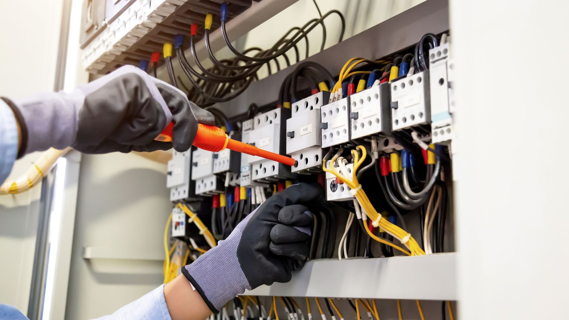 Electrician working on electrical panel with colorful wires and circuit breakers